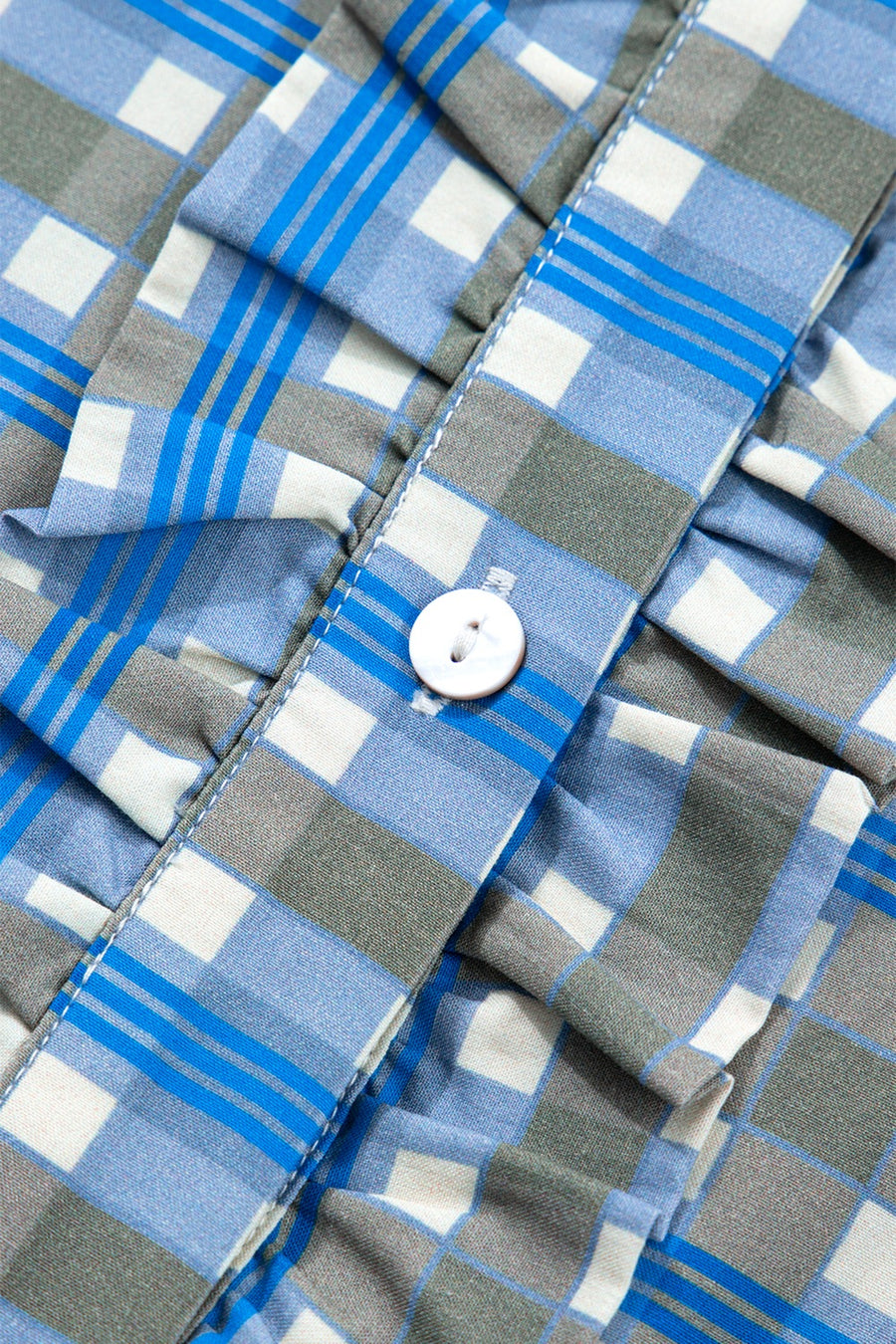 Blue plaid button-down blouse with frilled detail and white button.