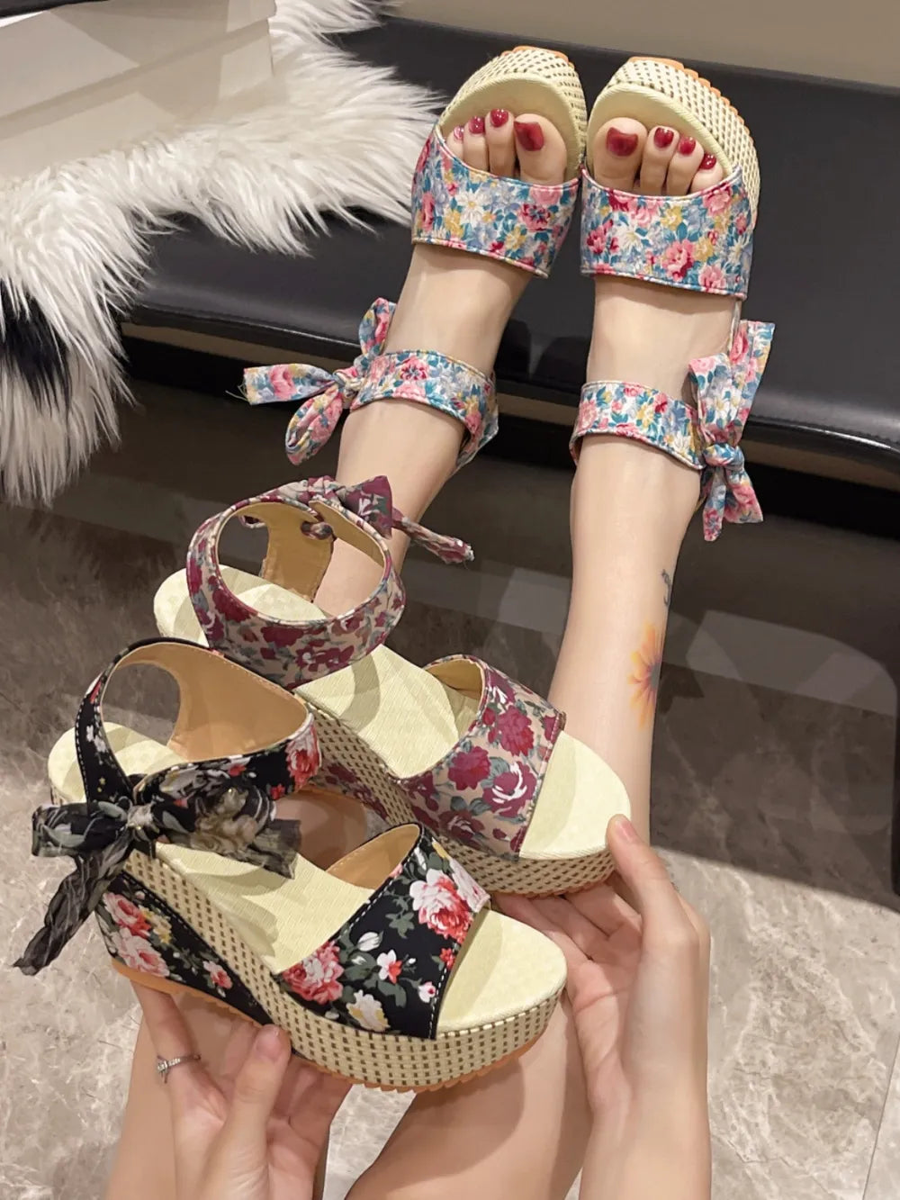 Floral bow wedge sandals with ankle straps and peep toe, available in black and cerise floral prints.