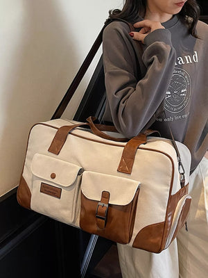 Sophisticated canvas travel bag in cream white with brown leather accents and multiple pockets.