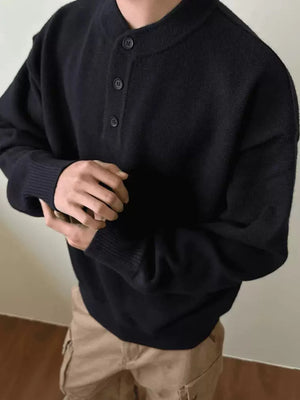 Black drop shoulder sweater with button detail and ribbed cuffs.