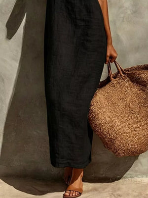 Black linen-blend maxi dress with a relaxed fit, styled with a straw tote bag.