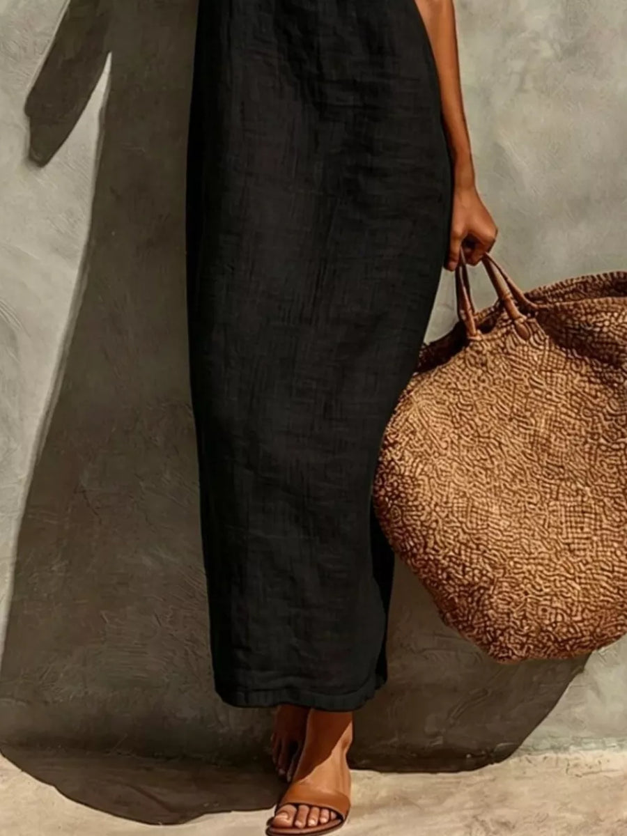 Black linen-blend maxi dress with a relaxed fit, styled with a straw tote bag.