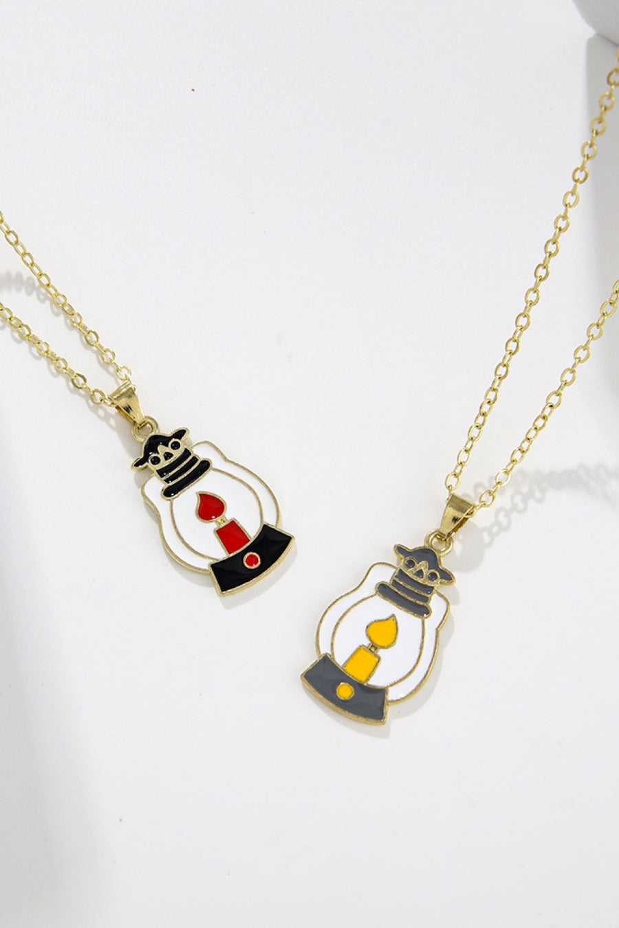 Spooky Season enamel pendant necklaces with lantern charms, one with red flame, one with yellow flame.