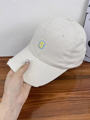 Baseball cap in cream cotton with embroidered yellow and blue S, distressed brim.