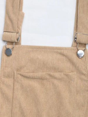 Tan corduroy overall dress with silver buckle straps and a front pocket.