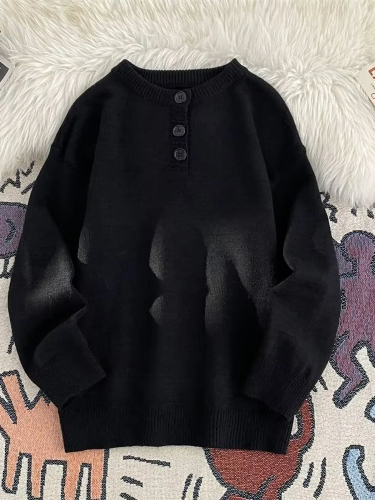 Black ribbed knit long-sleeve sweater with button detail at the neckline