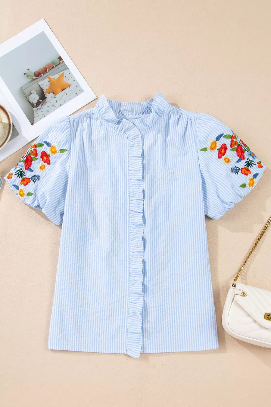Blue striped cotton shirt with embroidered floral puff sleeves and ruffled placket.