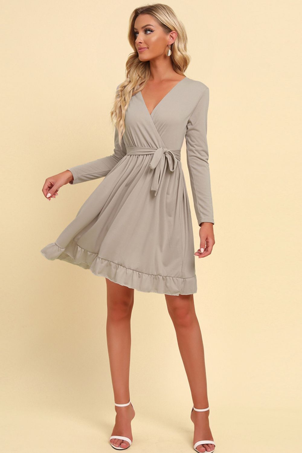 Tan wrap dress with V-neck, tie waist, long sleeves, and ruffled hem.