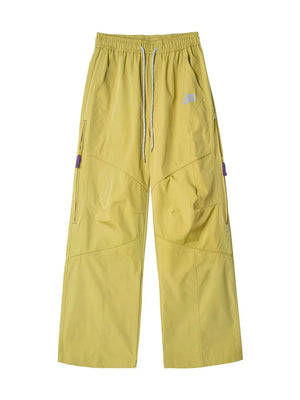 Relaxed fit mustard yellow cargo active pants with drawstring and purple zipper details.