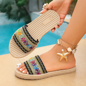 Bohemian woven strap flat sandals with colorful embroidered detail and seashell anklet.