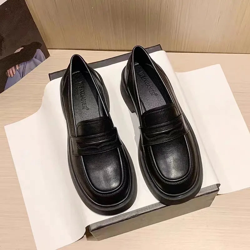 Black leather platform penny loafers with a chunky sole and classic strap detail.