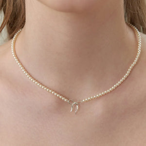 Delicate pearl choker necklace with a silver bow pendant.
