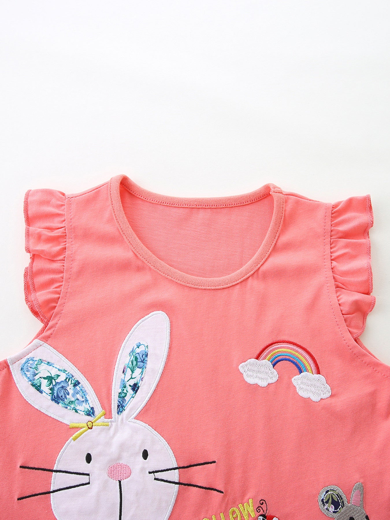 Coral cotton toddler top with bunny and rainbow appliques, ruffle sleeves.