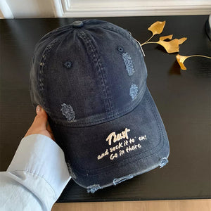 Distressed navy denim baseball cap with embroidered text and frayed details.
