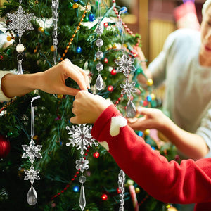 Transparent acrylic snowflake and icicle Christmas ornaments hang on a tree.