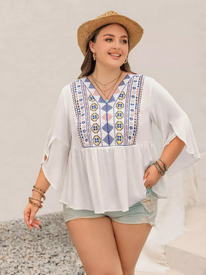 White plus size shirt with vibrant geometric embroidery, V-neck, and bell sleeves.