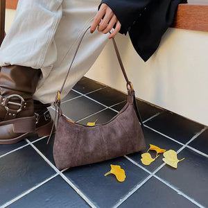 Chic suede crescent shoulder bag in coffee brown with adjustable strap.