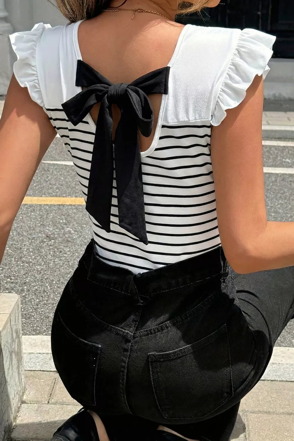 Chic striped tank top with ruffled sleeves and a black knot back detail.