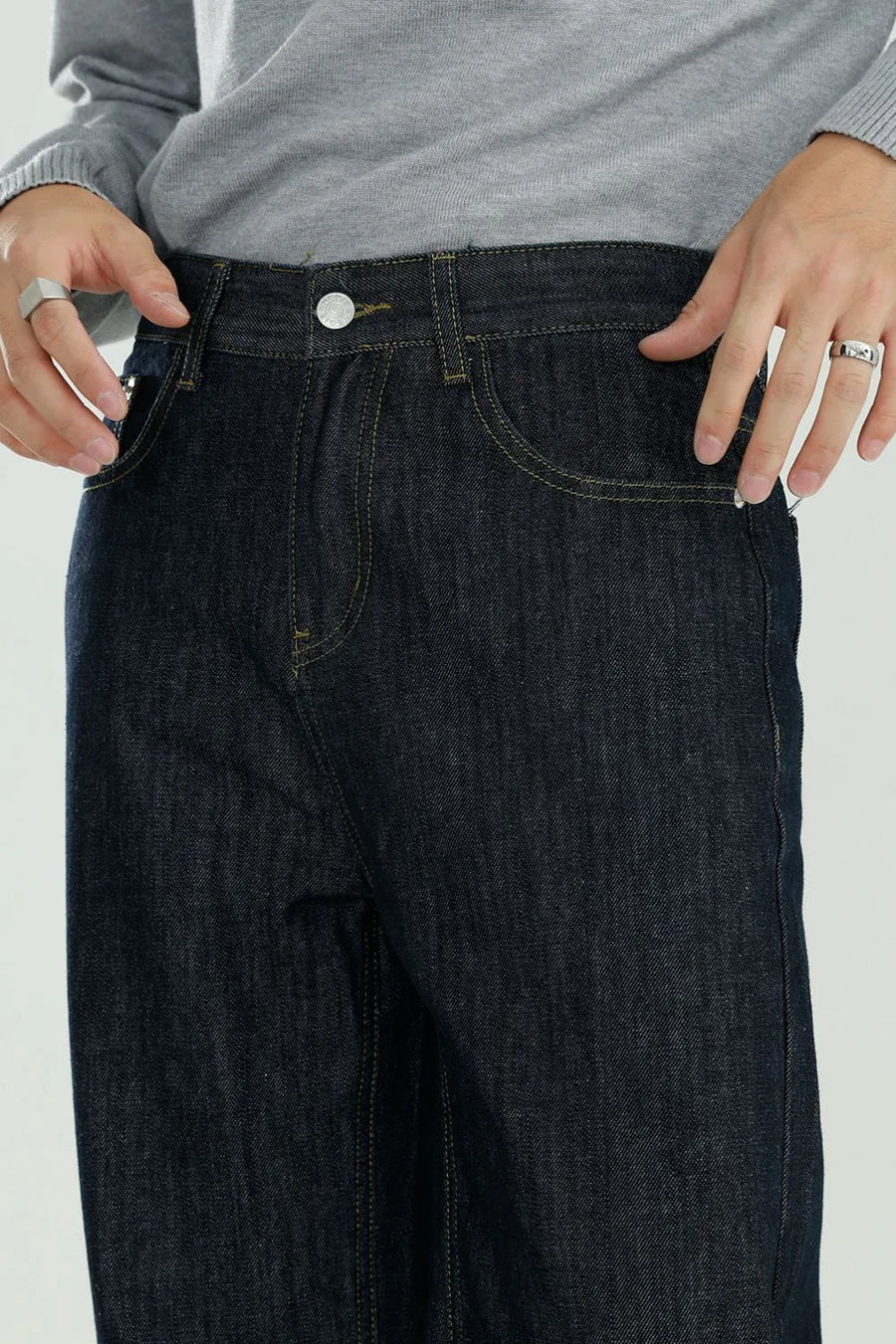 Dark wash wide-leg denim jeans with relaxed fit and yellow stitching.