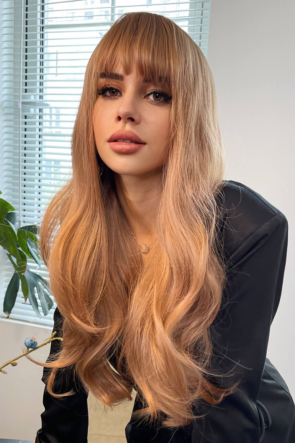 Strawberry blonde wig with baguette bangs and sunset waves, styled casually.