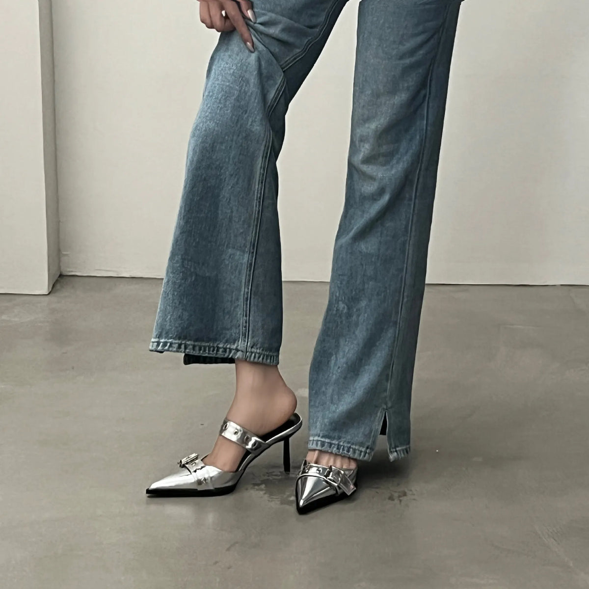 Silver pointed buckle mule heels with a strap and buckle detail.