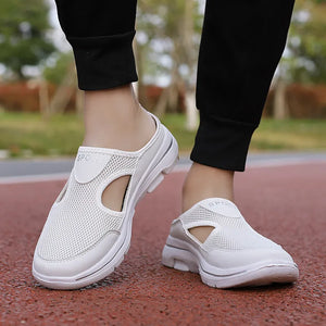 White mesh cut-out mule slippers with "SPORT" detail, worn with black pants.