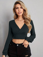 Textured wrap-front crop top in black with long sleeves and a deep V-neck.