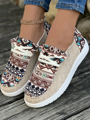 Aztec print canvas slip-on flats in tan with a white sole and decorative tie detail.