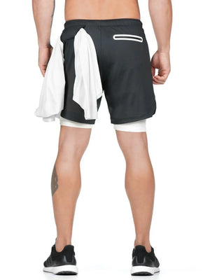 Black layered performance shorts with white built-in compression shorts and a white towel tucked into the waistband.