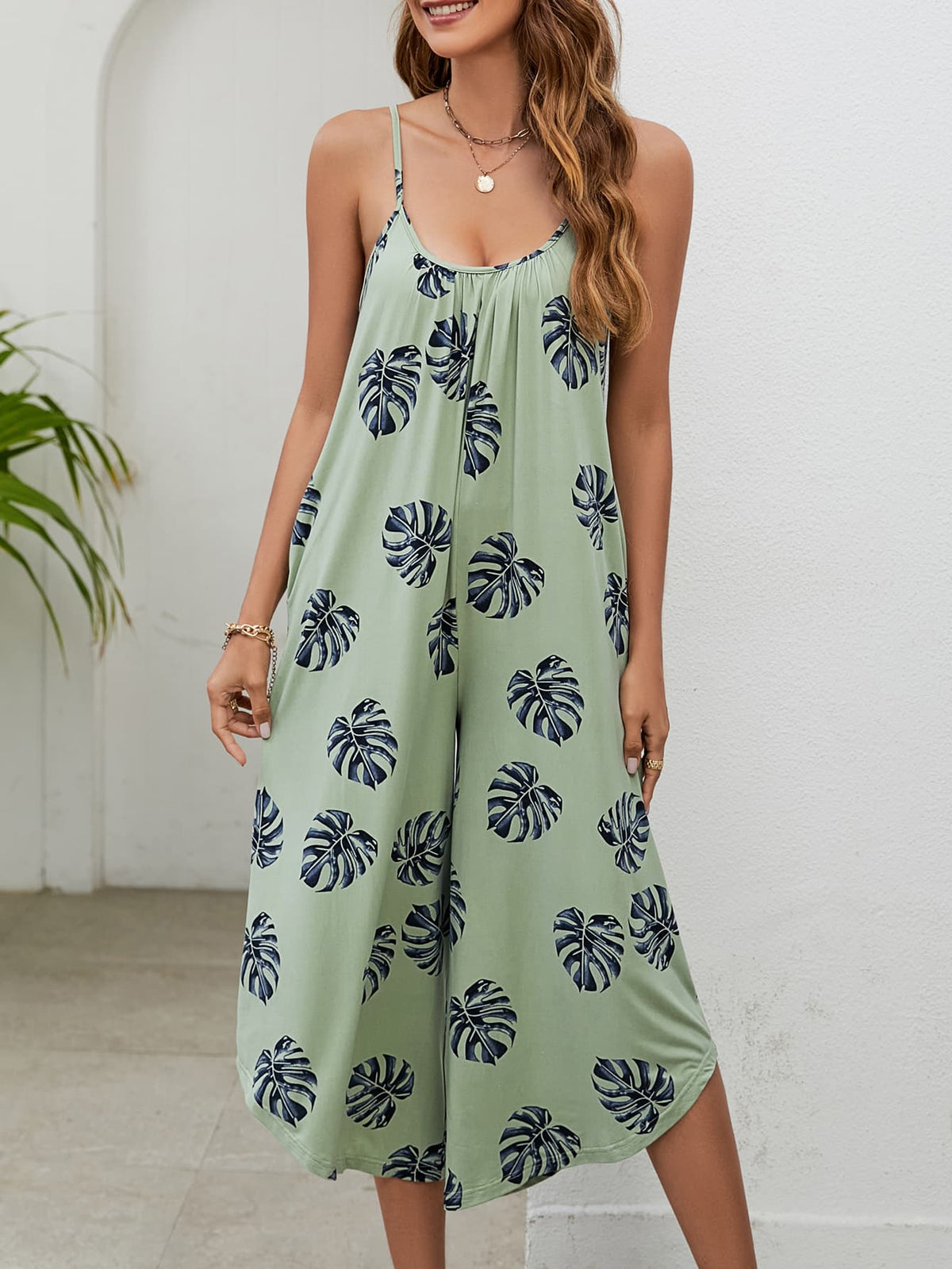 Sage green culotte jumpsuit with monstera print, gathered bust and spaghetti straps.