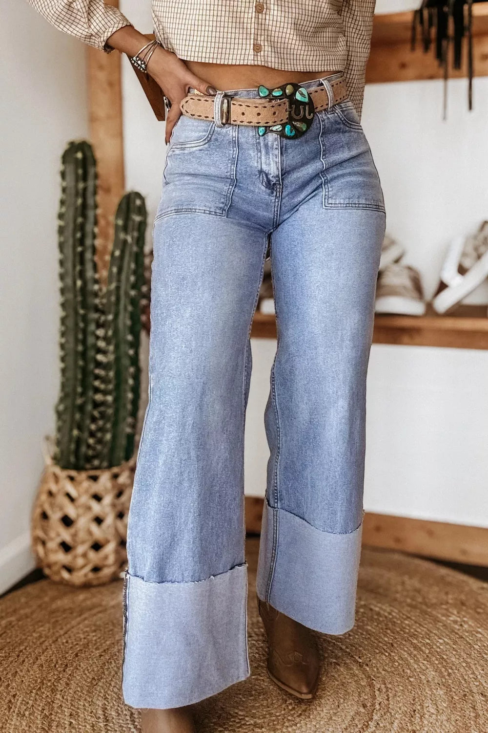 Light wash denim wide leg jeans with large cuffs and contrast pocket details.