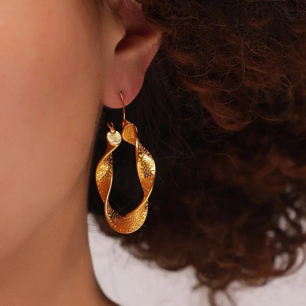 Textured spiral gold hoop earrings with a twisted design.