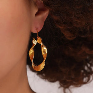 Textured spiral gold hoop earrings with a twisted design.
