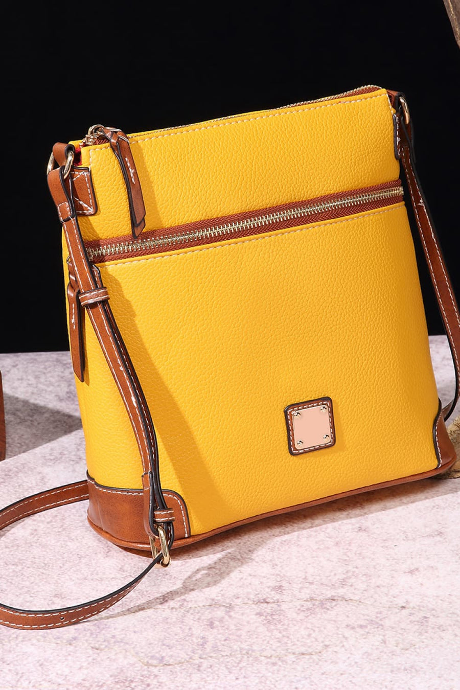 Yellow leather crossbody bag with brown trim and a zippered top compartment.