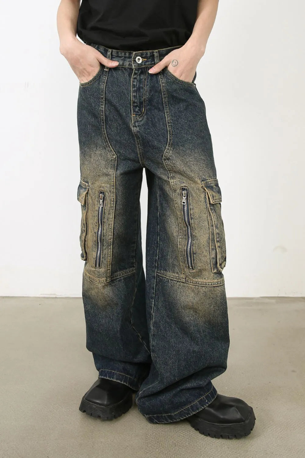 Distressed dark wash wide-leg denim cargo pants with zip pockets and a relaxed fit.