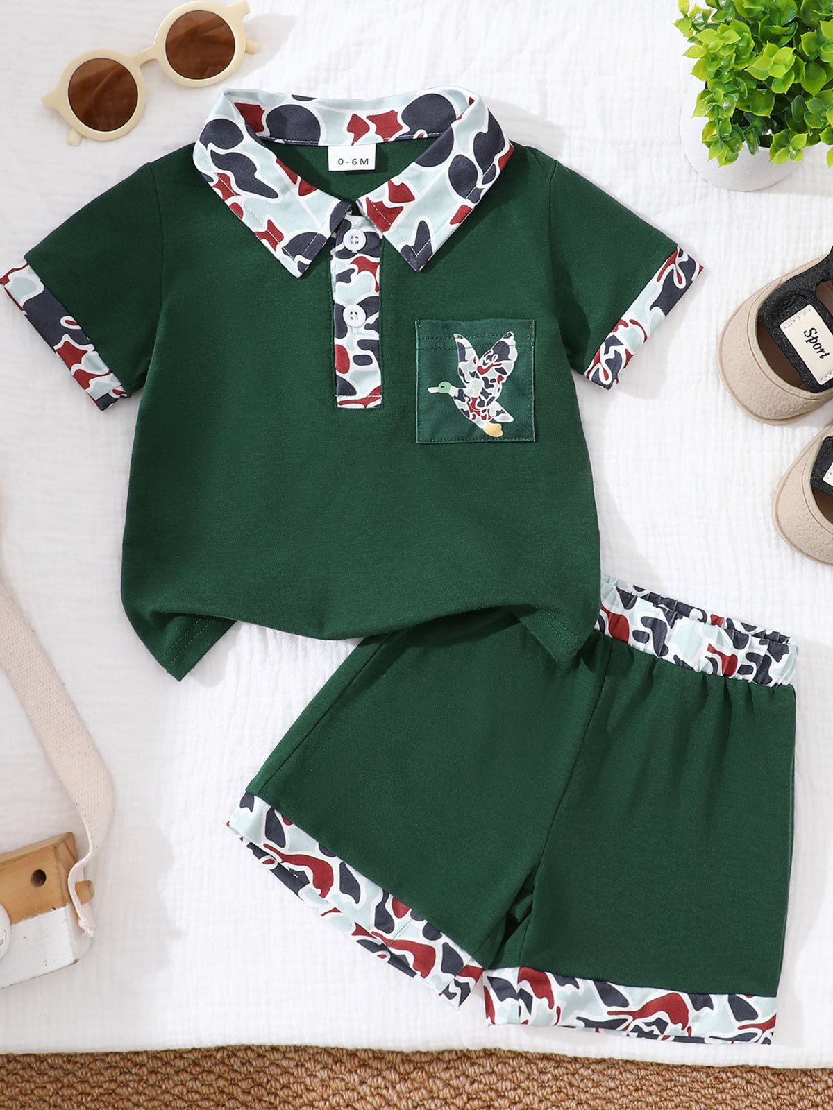 Dark green baby polo shirt and shorts set with camouflage trim and duck pocket detail.