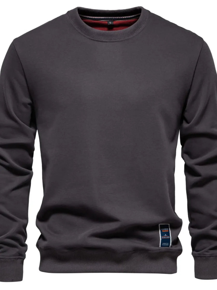 Gray crewneck sweatshirt with subtle patch detail on hem