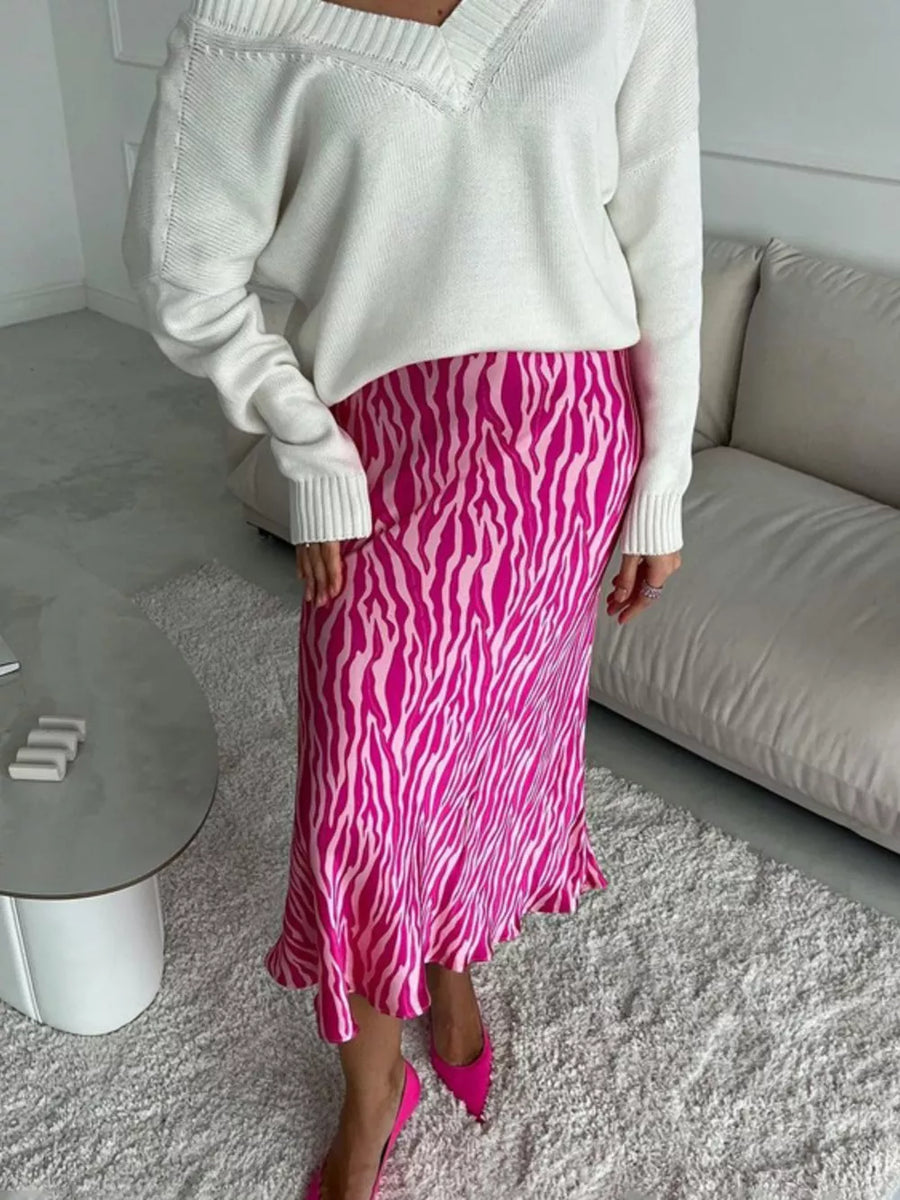 Satin midi skirt with pink zebra print and ruffled hem, paired with a white V-neck sweater.