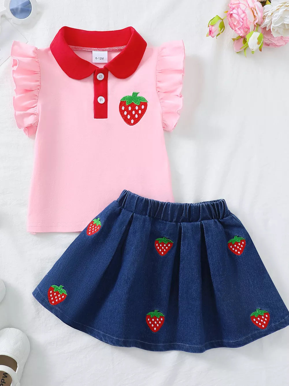 Pink polo top with strawberry embroidery and red collar, paired with a denim skirt with strawberry pattern.