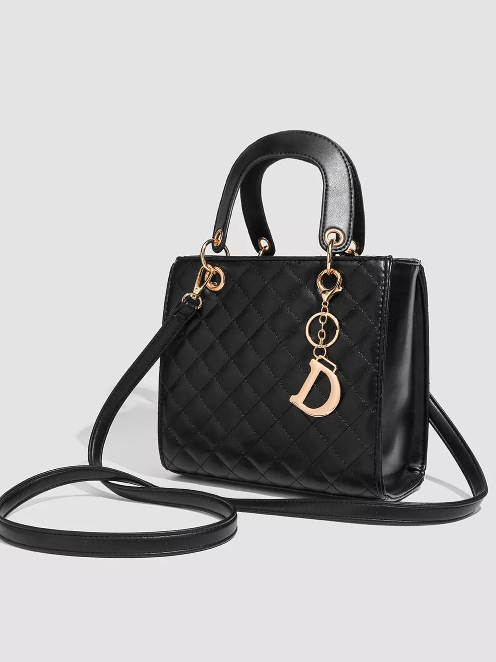 Mini quilted top-handle tote bag in black with gold hardware and a decorative 'D' charm.