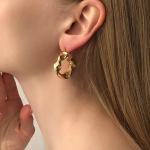 Gold textured hoop earrings with a twisted knot design.
