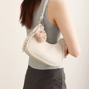 Mini crescent shoulder bag in cream with teddy bear charm and striped scarf detail.