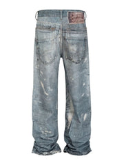 Medium wash distressed wide-leg denim jeans with paint splatters and a leather patch.