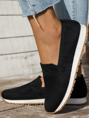Black knit slip-on sneakers with white soles and tan outsoles.