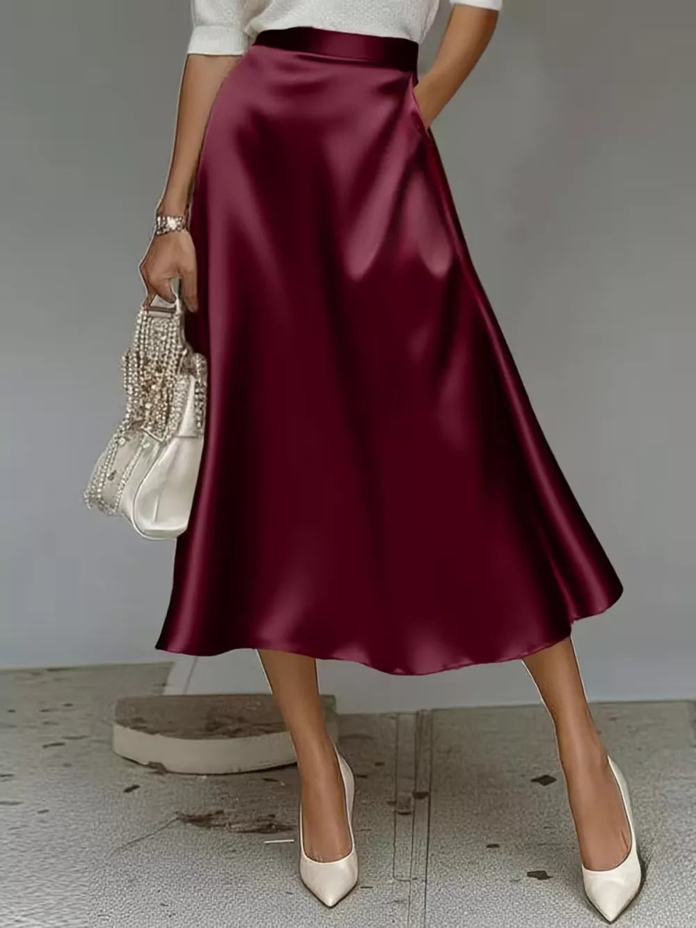 Elegant A-line satin skirt in wine red with pockets and a flowing silhouette.