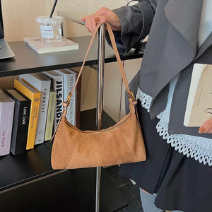 Chic suede crescent shoulder bag in coffee brown with adjustable strap.