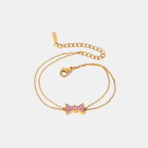 Gold chain bracelet with a pink gemstone bow charm