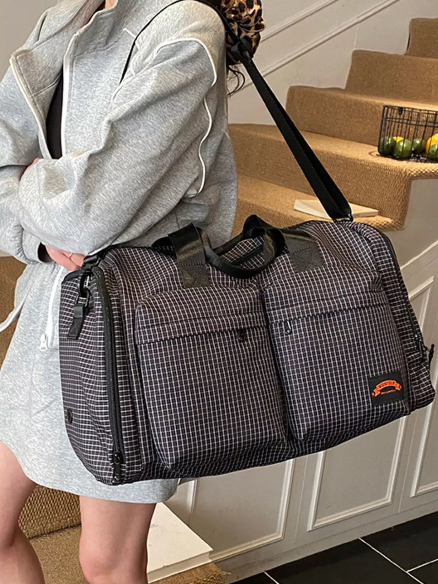 Chic medium plaid duffel bag with multiple exterior pockets and a black strap.