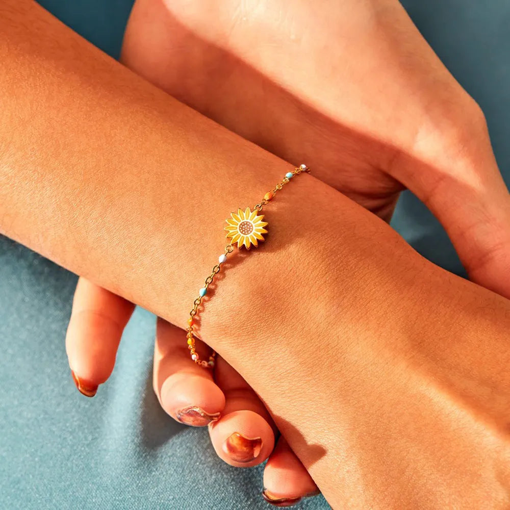 Gold beaded bracelet with a yellow sunflower charm and colorful accent beads.