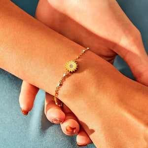 Gold beaded bracelet with a yellow sunflower charm and colorful accent beads.